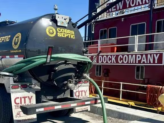 A Cobra Septic truck alongside a barge at a Miami-Dade dock